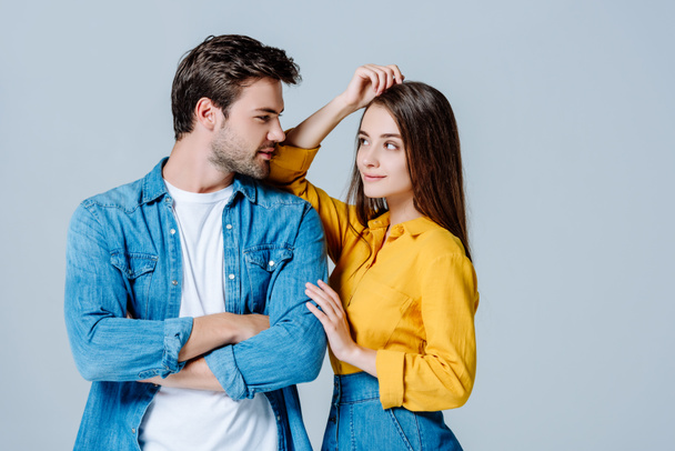 young couple in denim looking at each other isolated on grey - Photo, Image