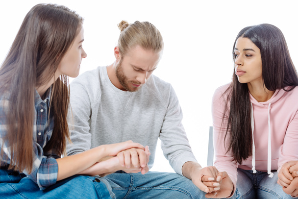 girls in support group holding hands with sad man on chair isolated on white - Foto, Imagen