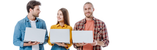 jóvenes amigos positivos sosteniendo ordenadores portátiles aislados en blanco, plano panorámico
 - Foto, imagen