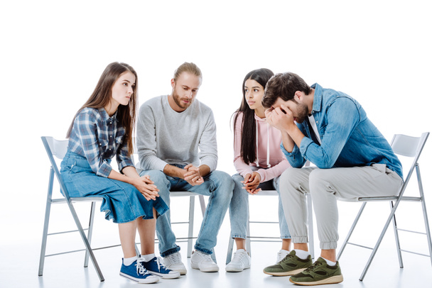sad multicultural support group sitting on chairs isolated on white - Valokuva, kuva