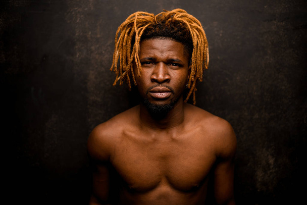 Naked black guy with blonde dreadlocks posing in the studio looking at camera - Фото, изображение