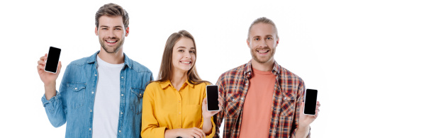 smiling three young friends holding smartphones with blank screens isolated on white, panoramic shot - 写真・画像