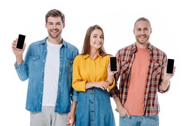 Lächelnd halten drei junge Freunde Smartphones mit weißen Bildschirmen in der Hand - Foto, Bild