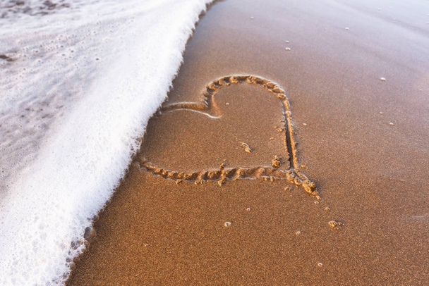 Καρδιά ζωγραφισμένη στην άμμο της παραλίας, απαλό κύμα της θάλασσας. Έννοια αγάπης. - Φωτογραφία, εικόνα