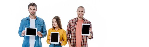 sonriendo a tres jóvenes amigos sosteniendo tabletas digitales con pantallas en blanco aisladas en blanco, plano panorámico
 - Foto, Imagen