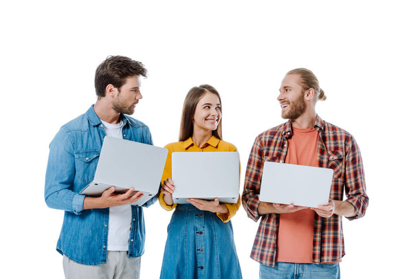 glimlachen drie jonge vrienden houden laptops geïsoleerd op wit - Foto, afbeelding