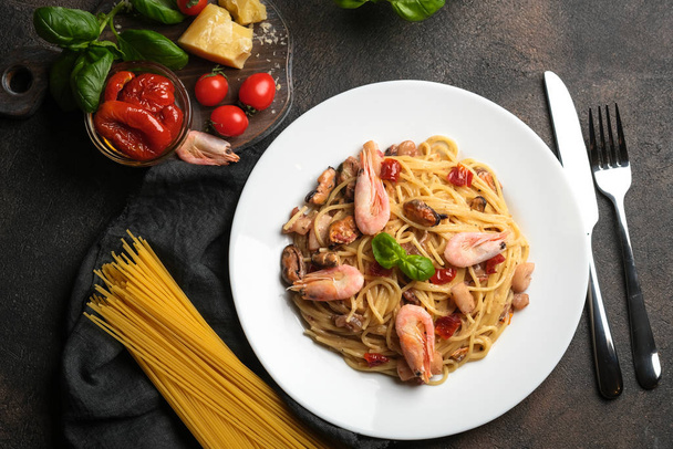 Pâtes aux fruits de mer. Une assiette de spaghettis aux crevettes, tomates séchées au soleil, basilic et parmesan avec des ingrédients sur un fond sombre. Espace de copie
. - Photo, image