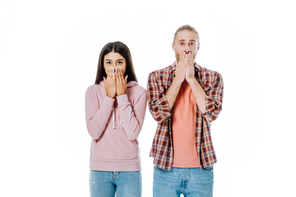 shocked young interracial couple covering mouths with hands isolated on white - Fotoğraf, Görsel