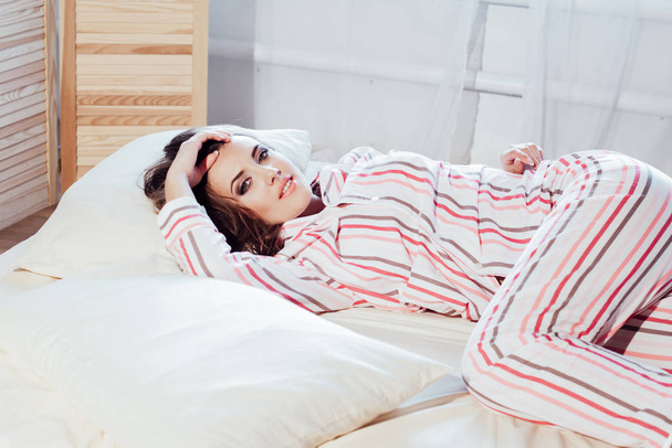 meisje in pyjama woke up in de ochtend is zittend op een bed - Foto, afbeelding