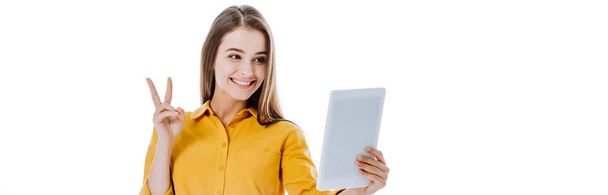 szczęśliwa atrakcyjna dziewczyna trzyma cyfrowy tablet i pokazuje znak pokoju na białym, panoramicznym ujęciu - Zdjęcie, obraz