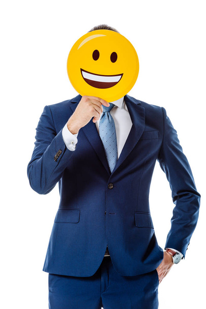KYIV, UKRAINE - AUGUST 12, 2019: businessman in blue suit holding happy smiley in front of face isolated on white - Photo, image