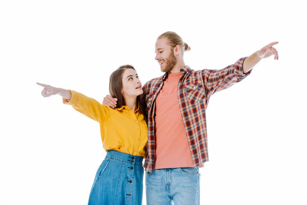 young couple in casual outfit pointing with fingers away and looking at each other isolated on white - Foto, Imagen