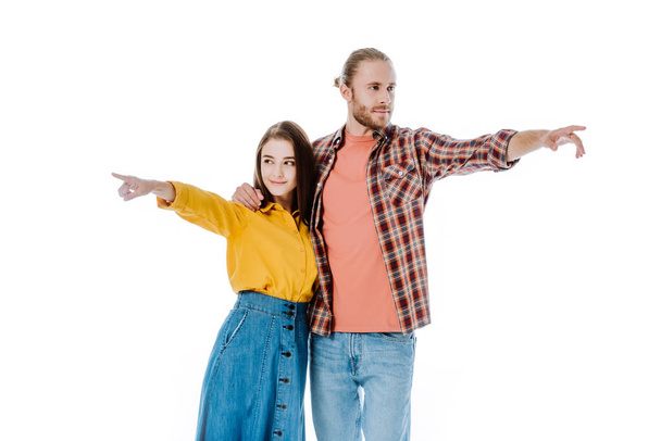young couple in casual outfit pointing with fingers away isolated on white - Zdjęcie, obraz