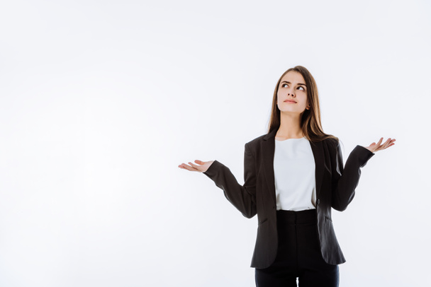 confused businesswoman in suit showing shrug gesture isolated on white - 写真・画像