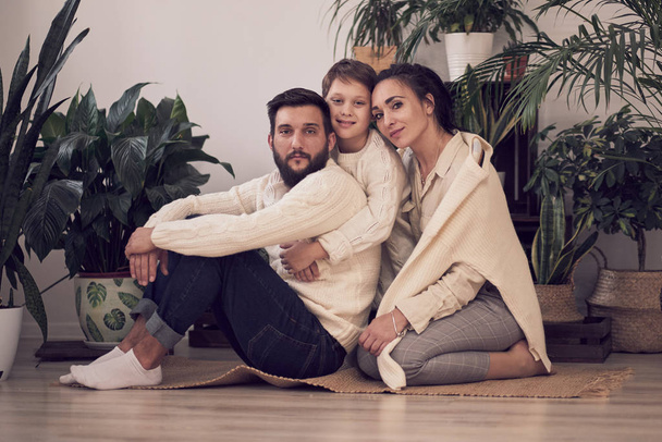 glückliche Familie. Vater, Mutter und Junge. Zusammensitzen auf dem Boden in gestrickten weißen Pullovern - Foto, Bild
