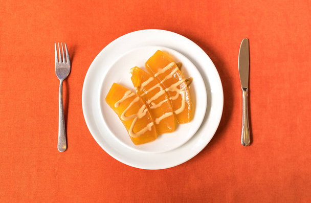Sladké lahodné a chutné dýně džem nebo dýně dýně squash marmeládový dezert v talíři na oranžovém stole pozadí z pohledu shora. To je tradiční turecký dezert nebo džem z pohledu shora - Fotografie, Obrázek