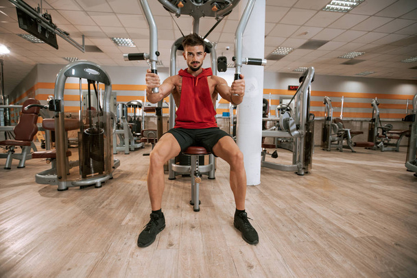 Мускулистый атлетичный молодой человек бодибилдер фитнес-модель, фокусирующаяся на упражнениях с в тренажерном зале
 - Фото, изображение