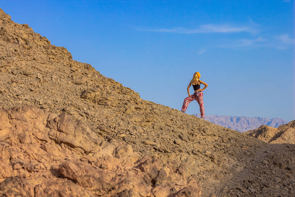 Reise Fotografie Konzept lustige Frau posieren in fröhlicher Stimmung auf Wüstensand Stein felsigen Berg szenische Landschaft Umgebung auf leeren blauen Himmel Hintergrund, Kopierraum  - Foto, Bild