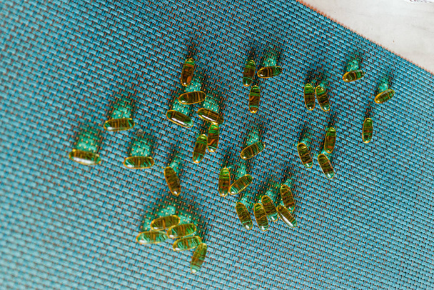 Капсули з риб'ячим жиром з омега-3 та вітаміном D у пластиковій пляшці на блискучій текстурі з сонячними променями, концепція здорового харчування
 - Фото, зображення