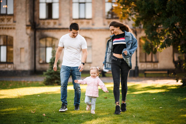 Mother and father running with a little daughter in the park - Foto, immagini