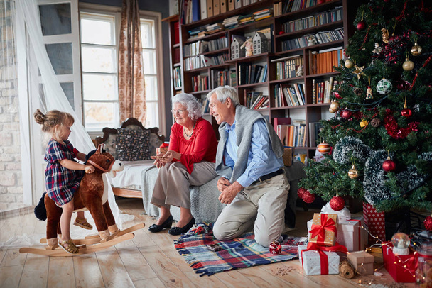 Grandparents with their granddaughter next to Christmas tree  - Foto, afbeelding