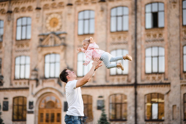Father playing with daughter tossing her up - Zdjęcie, obraz