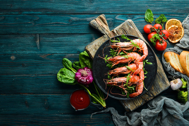 Boiled shrimp and arugula in a black plate. Seafood dishes. Top view. Free space for your text. - 写真・画像