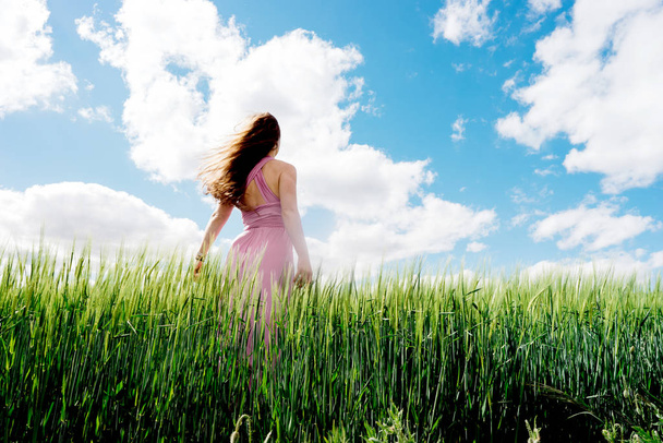 Long-haired woman in a dress on a field of blue wheat - Zdjęcie, obraz