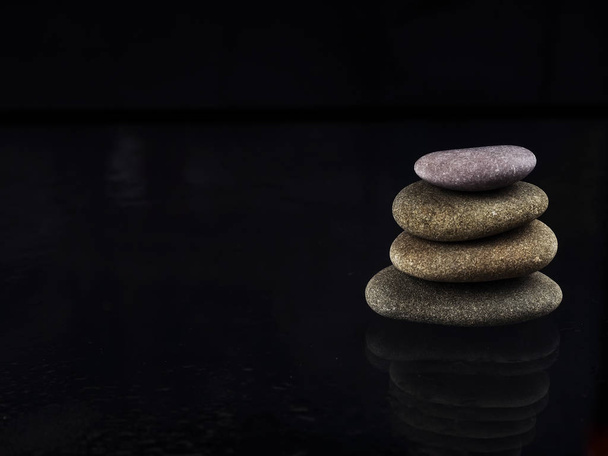 Fürdőkövek. fekete fényes zen kövek vízcseppekkel fekete háttér felett. Zen kövek felhalmozódnak esőcseppekben, a nyugalom és a béke fogalma. - Fotó, kép