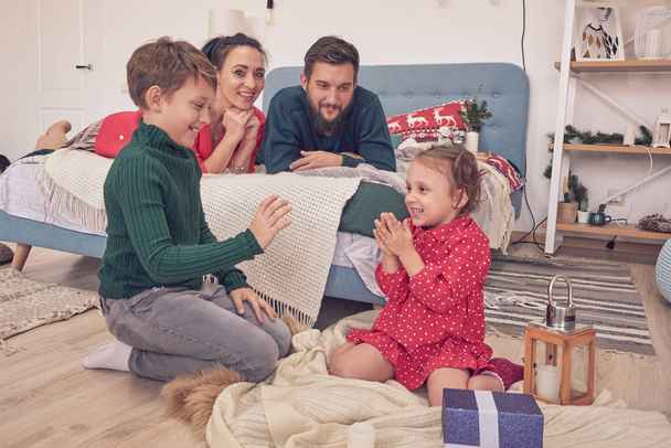 little boy girl having fun, friendship between siblings, family leisure time in living room. Children sister and brother playing drawing together on floor while young parents relaxing at home on sofa - Photo, Image