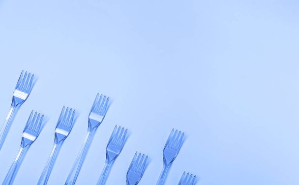Plastic fork pattern on classic blue background. - Photo, Image