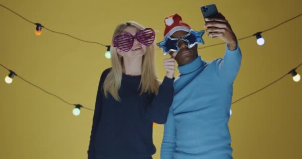 Νεαρός άντρας και γυναίκα βγάζουν selfie σε κίτρινο φόντο - Πλάνα, βίντεο