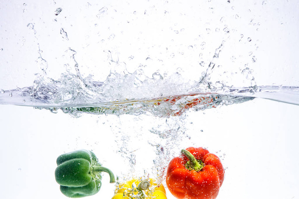 three peppers falling in water - Foto, immagini