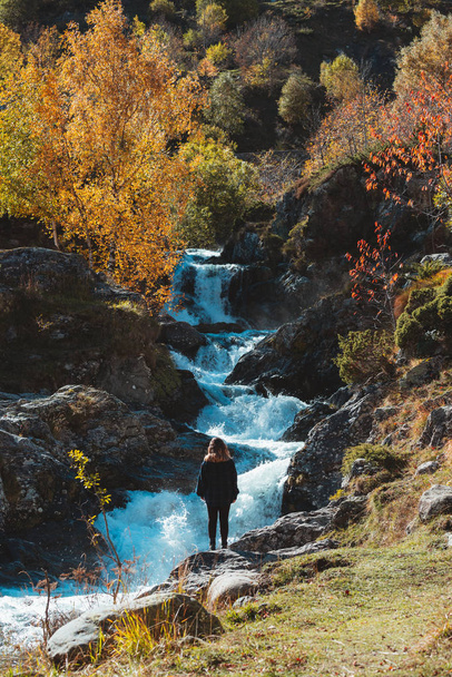 Menina caucasiana loira assistindo uma cachoeira entre árvores coloridas de outono - Foto, Imagem