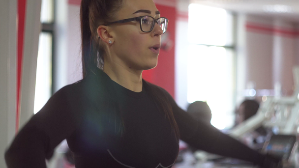 Hermosa chica en gafas en el club deportivo hace diferentes tipos de ejercicios
 - Metraje, vídeo