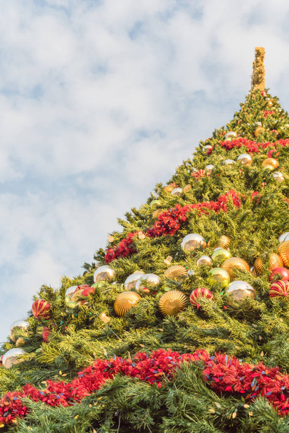 Χαμηλή προοπτική γκρο πλαϊνή άποψη του εξήντα πόδι χριστουγεννιάτικο δέντρο με πολύχρωμα μπιχλιμπίδια και φώτα - Φωτογραφία, εικόνα