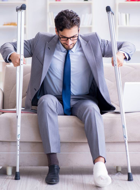 Üzletember mankóval és törött lábbal otthon dolgozik - Fotó, kép