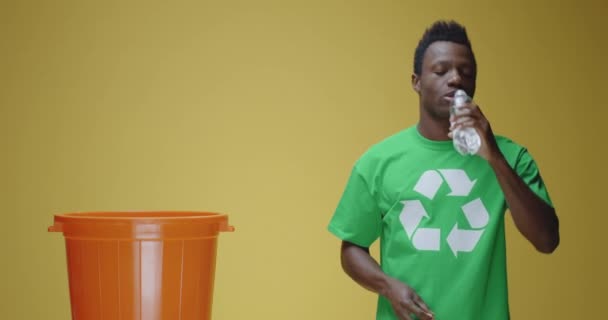 Mladý muž házení plastové láhve recyklovat bin - Záběry, video