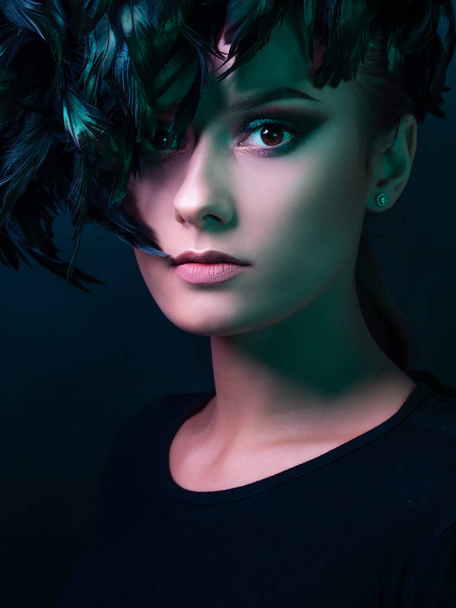 Beautiful young woman in mysterious emerald light. Hat of black feathers, - Foto, immagini