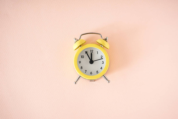 Flat lay Yellow alarm clock on a beige background. - Photo, Image