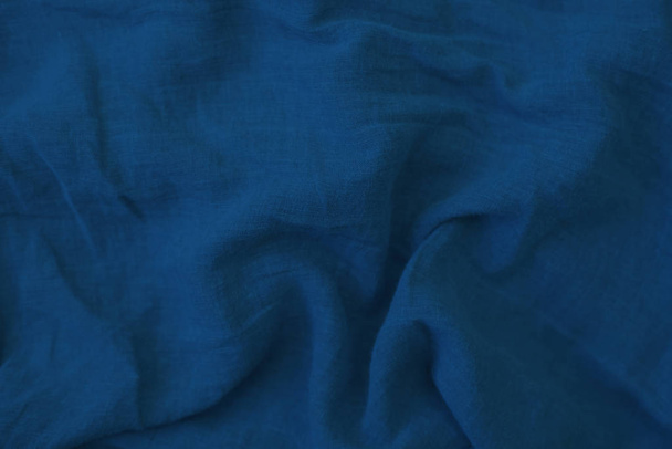 Crumpled blue fabric texture close up. Trendy tone of 2020 classic blue color - Фото, изображение