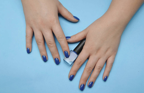 Mano femenina con manicura de moda en color azul clásico. Color del año 2020
. - Foto, imagen