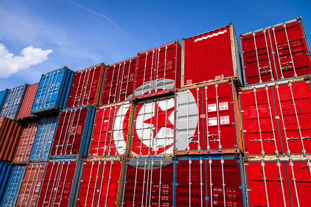 die Nationalflagge der Tunesier auf einer großen Anzahl von Metallcontainern zur Lagerung von Waren, die reihenweise übereinander gestapelt sind. Konzeption der Lagerung von Waren durch Importeure, Exporteure - Foto, Bild