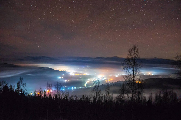 Night city in the fog in the mountains in autumn - 写真・画像