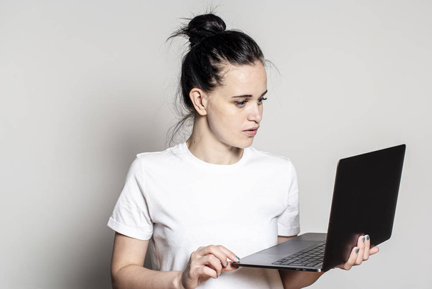 Jovem mulher olha para seu laptop e lê cuidadosamente o e-mail, ela está agradavelmente surpreso com a boa notícia
. - Foto, Imagem