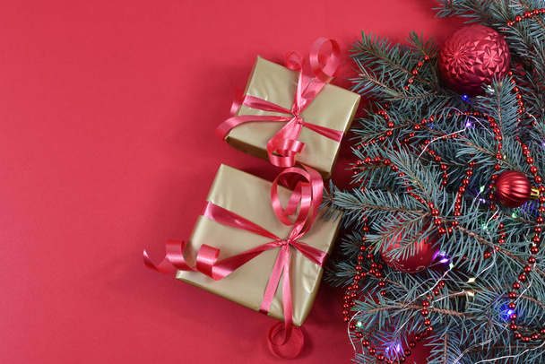 Δώρα κοντά στο χριστουγεννιάτικο δέντρο σε κόκκινο φόντο. Κόκκινες μπάλες Χριστουγέννων. - Φωτογραφία, εικόνα