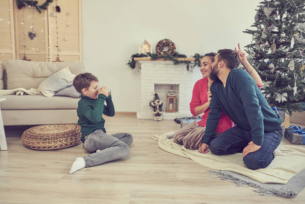 A fia képeket készít apáról és anyáról. pár pózol alatt karácsonyfa fotós fia - Fotó, kép