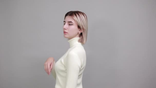 Tiukka nuori nainen valkoinen pusero, kädestä leuka yli harmaa seinä
 - Materiaali, video