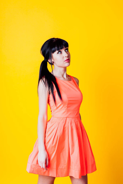 黄色の背景にオレンジ色のドレスの女の子 - 写真・画像