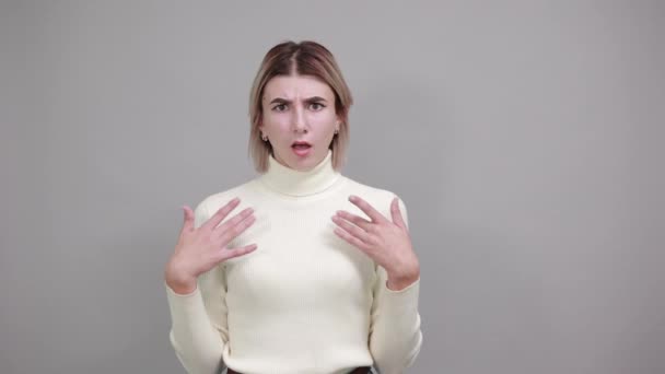 Portrét usmívající se mladé ženy v pastelovém svetru ukazující prsty na hrudi - Záběry, video